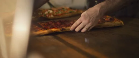 Delicious al taglio pizzas with different toppings being placed on a wooden s Stock Footage 147518922