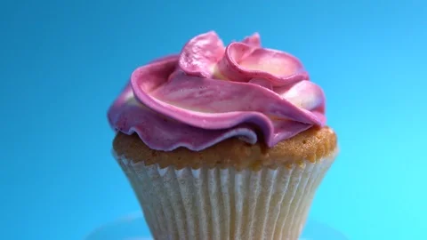 A delicious and appetizing capcake rotates against a blue background. Stock Footage 92683958