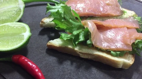 Delicious appetizer on the table. Two toasts with fresh red fish and salad Stock Footage 122555754