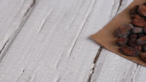 Delicious aromatic brown roasted cocoa beans on a white table Stock Footage 100593210