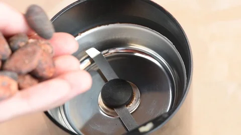 Delicious aromatic roasted cocoa beans are ground in a coffee grinder at home Stock Footage 94251759