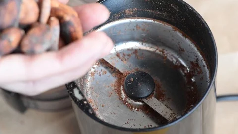 Delicious aromatic roasted cocoa beans are ground in a coffee grinder at home Stock Footage 94251771