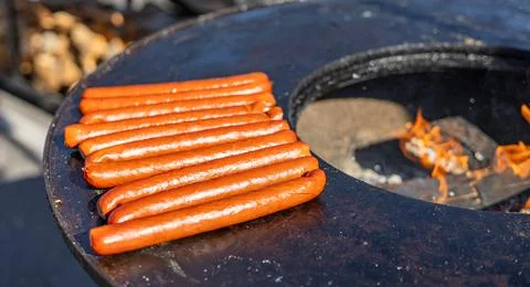 Delicious array of sausages sizzling on a flat top grill. The sausages are ar Stock Photos