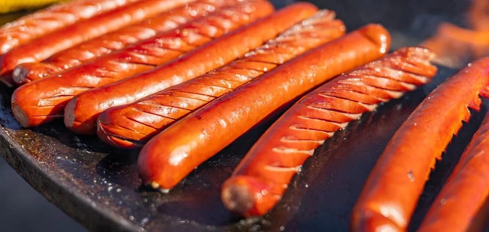 Delicious array of sausages sizzling on a flat top grill. The sausages are .. Stock Photos