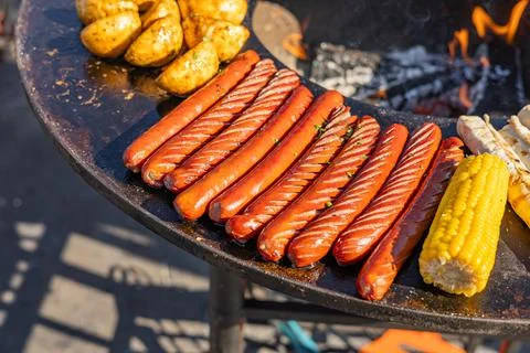 Delicious array of sausages sizzling on a flat top grill. The sausages are ar Stock Photos