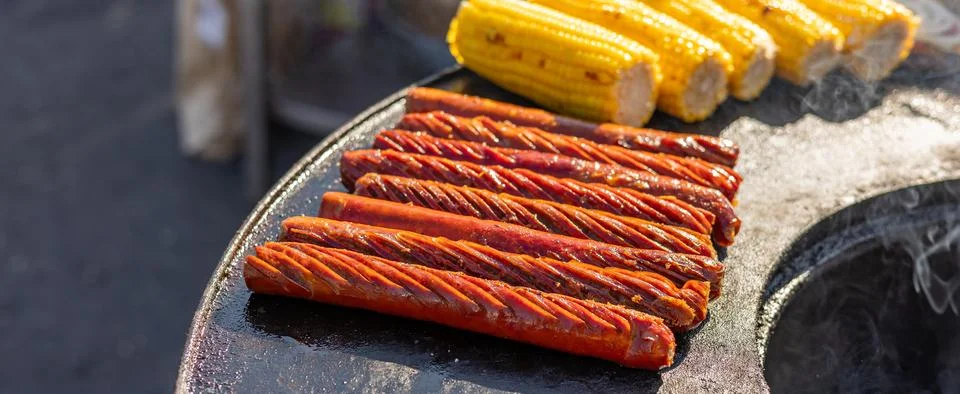 Delicious array of sausages sizzling on a flat top grill. The sausages are ar Stock Photos