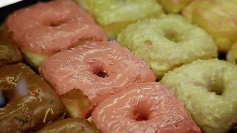A delicious assortment of square and round donuts arranged in rows, topped with Stock Footage 312676608