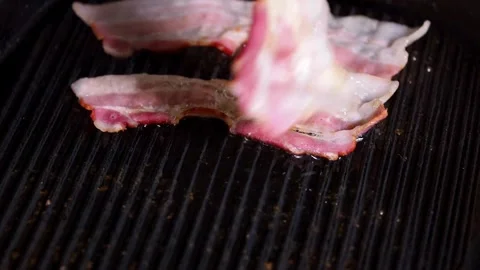 Delicious bacon slices being cooked, then being flipped by cooking tongs. 스톡 동영상 334642247