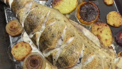 Delicious baked pike perch with fresh vegetables prepared in a cozy kitchen Stock Footage 336532710
