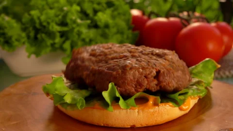 Delicious beef cutlet is falling onto the hamburger bun with green salad Stock Footage 127642909