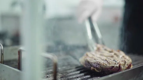 Delicious beef steak cooking in front of the camera on professional grill by the Stock Footage 156175792