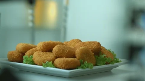 Delicious breaded chicken or turkey nuggets fall into a white flat plate Stock Footage 116873182
