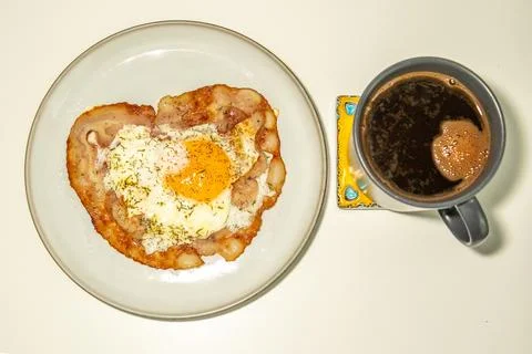Delicious breakfast with a fried egg on crispy bacon and a cup of black cof.. Stock Photos