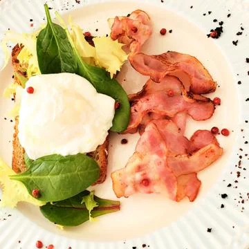 Delicious Breakfast poached egg with bacon and watercress Stock Photos