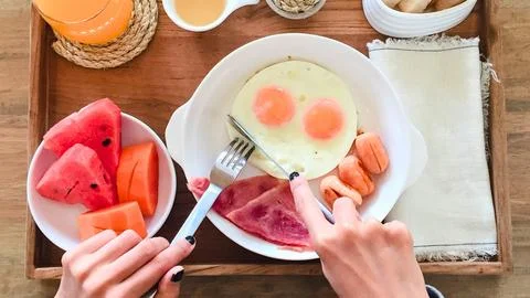 Delicious breakfast spread with eggs fruit and ham on a wooden tray Stock Photos