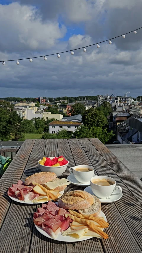 Delicious breakfast spread on wooden rooftop table with city view. Video stock 344879611