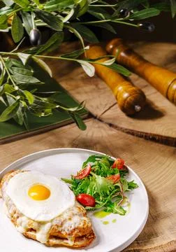 Delicious brunch plate with croissant, egg, and fresh salad at rustic setting Stock Photos