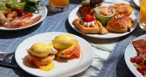 Delicious brunch spread with eggs benedict, pastries, and fresh juice Video stock 318119053