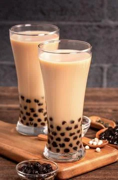 Delicious bubble milk tea with tapioca pearl ball in glass on wooden table an Foto stock