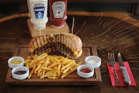 Delicious Burger served with crispy french fries and sauces on a wooden table Stock Photos