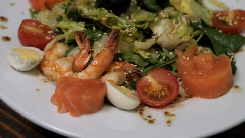 Delicious caesar salad with prawns and olives rotate on a large white plate. Stock Footage 144788858