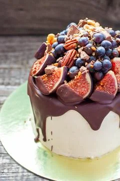 Delicious cake with figs dipped into melted chocolate, pecan nuts, grapes, ch Stock Photos