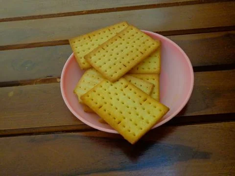 Delicious cheese flavored biscuits on a small plate and wooden background Fotos de archivo