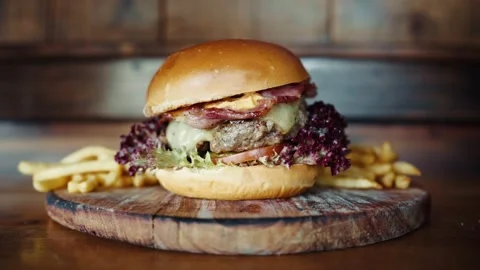 A delicious cheeseburger with quality beef patty on wooden board with crispy fri Stock Footage 183613554
