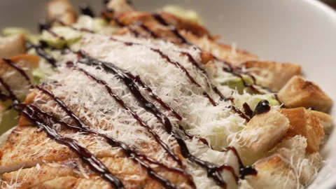 Delicious chicken caesar salad spinning in a white bowl with parmesan cheese Stock Footage 336678392