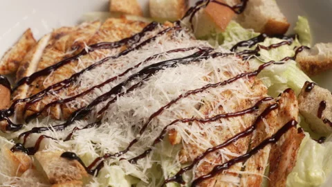 Delicious chicken caesar salad spinning in a white bowl with parmesan cheese Stock Footage 340542724