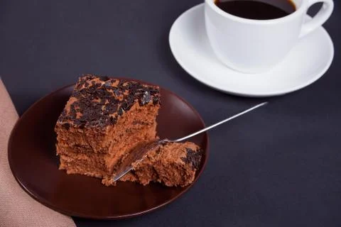 Delicious chocolate cake on the brown plate with cup of coffee on the black t Stock Photos