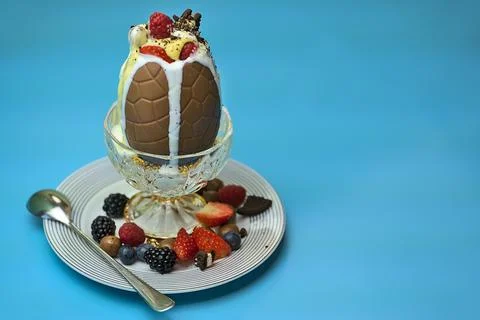 Delicious chocolate Easter egg topped with ice cream, berries, cookies, custard Stock Photos