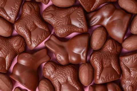 Delicious chocolate Easter eggs, bunnies and lambs over pink pattern backgrou Stock Photos
