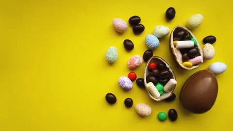Delicious chocolate easter eggs, sweets on yellow background Stock Photos