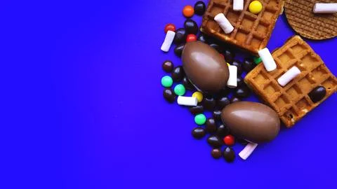 Delicious chocolate easter eggs, sweets on dark blue background Stock Photos