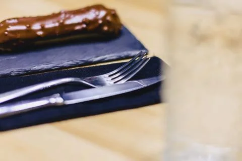 Delicious chocolate eclair with a fork and a knife Stock Photos