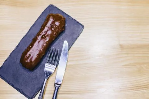 Delicious chocolate eclair with a fork and a knife Stock Photos