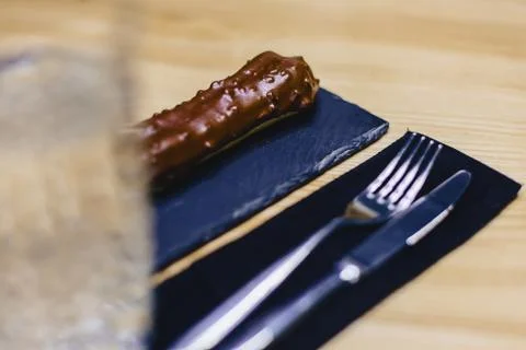 Delicious chocolate eclair with a fork and a knife Stock Photos