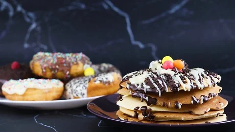 Delicious chocolate glazed donuts on the table with pancakes with chocolate 動画素材 128992875