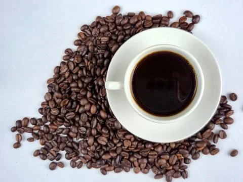 A Delicious Coffee Cup Elegantly Surrounded by Aromatic Coffee Beans That T.. Stock Photos