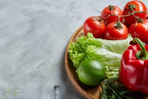 Delicious composition of assorted fresh vegetables and herbs on white textured Photos