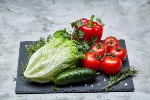 Delicious composition of assorted fresh vegetables and herbs on white textured Photos