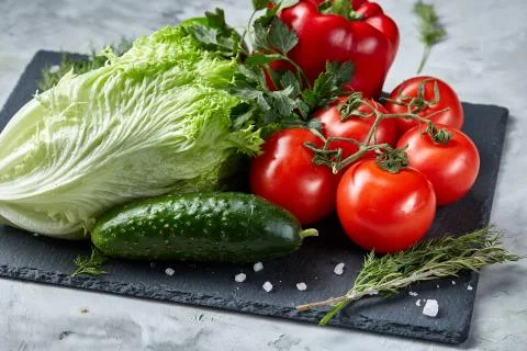 Delicious composition of assorted fresh vegetables and herbs on white textured Photos