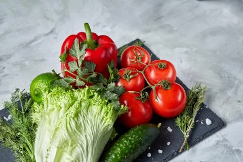 Delicious composition of assorted fresh vegetables and herbs on white textured Photos