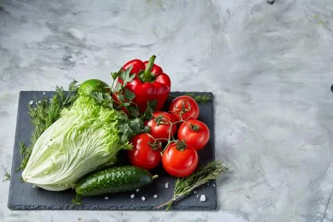 Delicious composition of assorted fresh vegetables and herbs on white textured Photos
