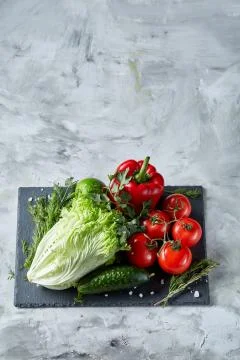 Delicious composition of assorted fresh vegetables and herbs on white textured Photos