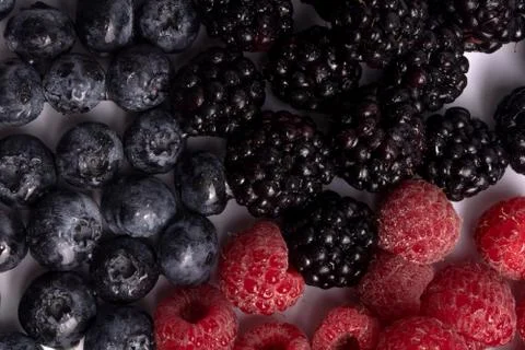 A delicious composition of three types of berries laying on white background Stock Photos