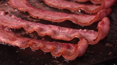 Delicious cooked bacon strips. Close-up of pork bacon slices on hot grilled pan. 스톡 동영상 334642027