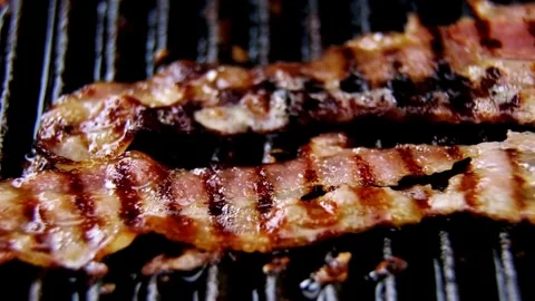 Delicious cooked bacon strips. Close-up of pork bacon slices on hot grilled pan. 스톡 동영상 334642097