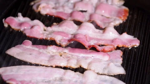 Delicious cooked bacon strips. Close-up of pork bacon slices on hot grilled pan. 스톡 동영상 334642147